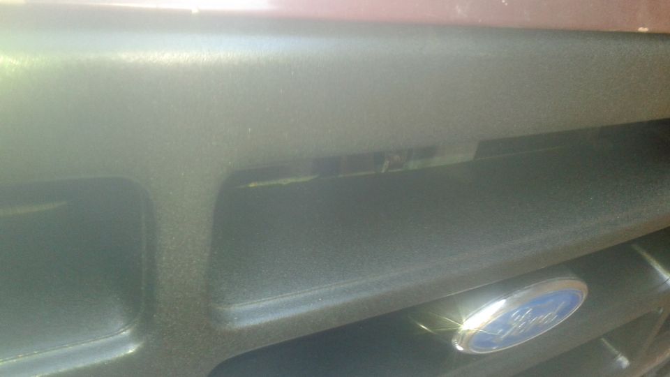 Close-up of a black Ford Bronco grille with a blue Ford emblem.