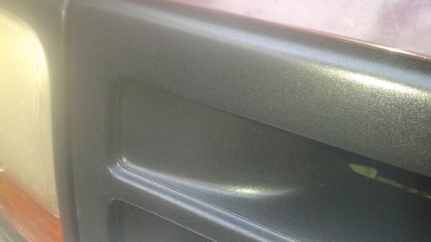 1996 Ford Bronco - A close-up, angled shot shows the textured, metallic dark gray paint on the driver's side door panel of a 1996 Ford Bronco. The headlight a…