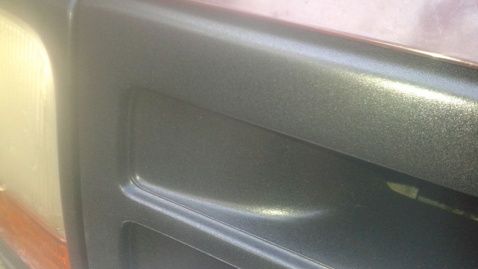 Close-up of metallic dark gray door panel and headlight on a 1996 Ford Bronco.