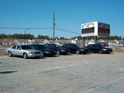2001 Ford Crown Victoria - A silver 2001 Ford Crown Victoria is parked in front of several black sedans under a bright blue sky.