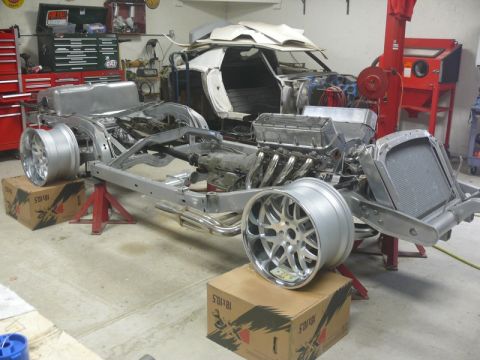 Car chassis with V8 engine and radiator in a garage.