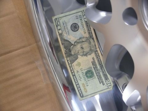 Twenty dollar bill on a shiny car part.