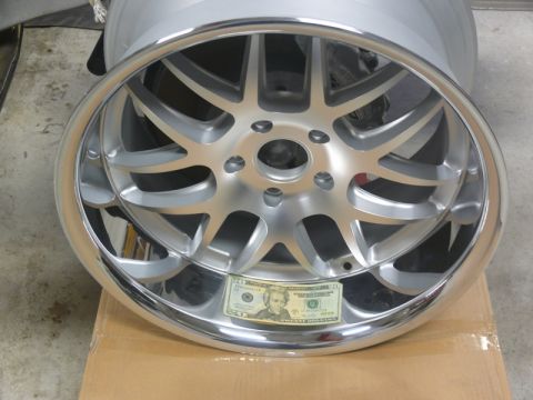 Polished chrome aftermarket wheel with a twenty-dollar bill inside.