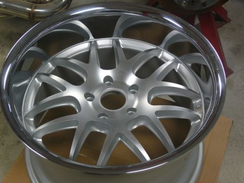 Silver aftermarket wheel with polished lip and multi-spoke design.