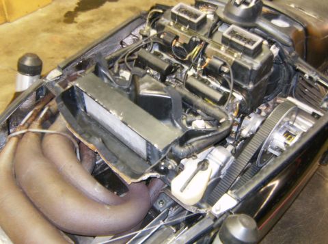 2000 Ford E350 - The engine compartment of a snowmobile is shown, featuring a complex arrangement of pipes, wiring, and engine components. The exhaust pipes…
