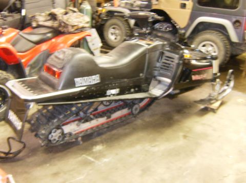 2000 Ford E350 - A black Yamaha snowmobile is parked indoors next to a red ATV and behind a tan Jeep Wrangler. The snowmobile has a Yamaha logo on its side…