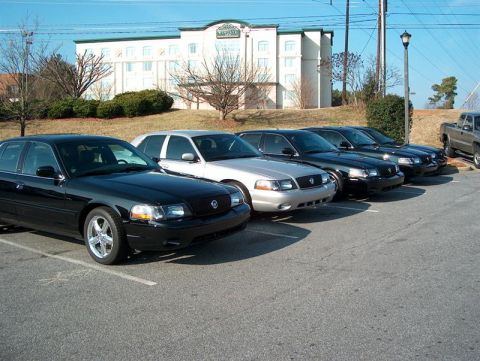 2001 Ford Crown Victoria - A line of Ford Crown Victoria police interceptors are parked in a lot outside a hotel.