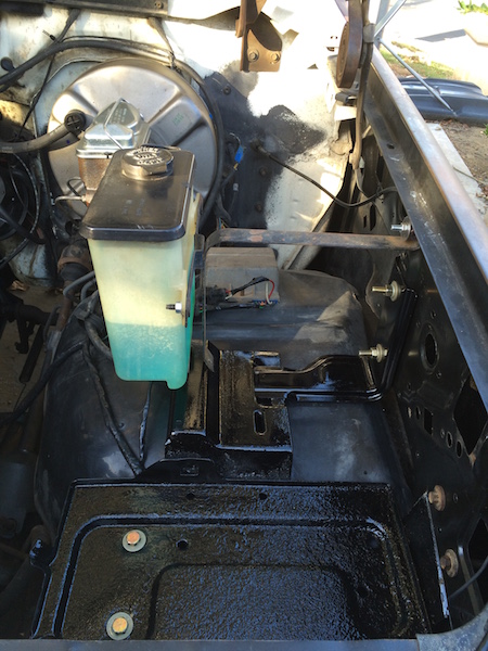 1981 Ford Bronco - The engine bay of a 1981 Ford Bronco shows a freshly painted black floor and components, with a clear fluid reservoir for the brake master…