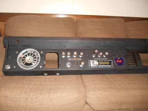 1972 Ford Bronco - A black dashboard panel from a 1972 Ford Bronco is shown, featuring a speedometer, several toggle switches, a radio, and a decorative emble…