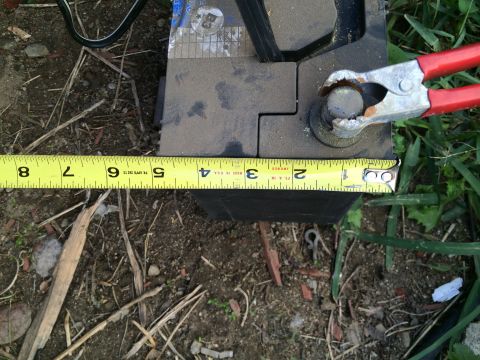 1987 Suzuki Samurai - Photograph of a battery measured with a tape measure, not a technical document.