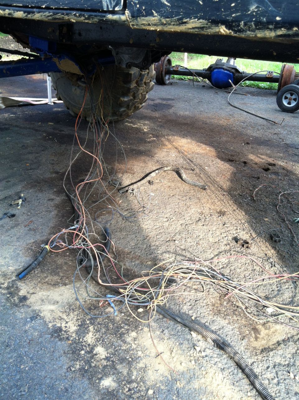 Tangled wires hanging from underside of a dark pickup truck.