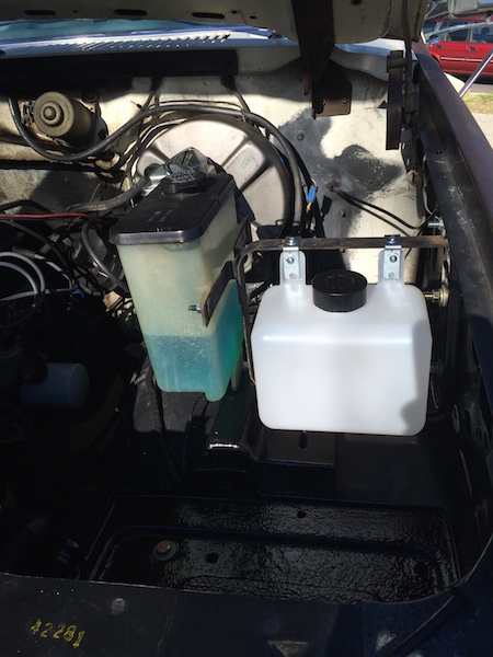 1981 Ford Bronco - Under the hood of a 1981 Ford Bronco, two fluid reservoirs are visible. A light blue fluid is in the taller reservoir on the left, and a wh…