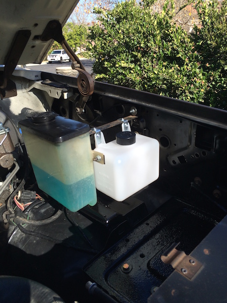 1981 Ford Bronco - The engine bay of a classic Ford Bronco shows two fluid reservoirs. The reservoir on the left is partially filled with blue fluid, while th…