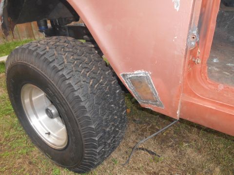 1972 Ford Bronco - A close-up view of the lower rear quarter panel of a vehicle, showing a patch that has been welded into place. A large off-road tire and wh…