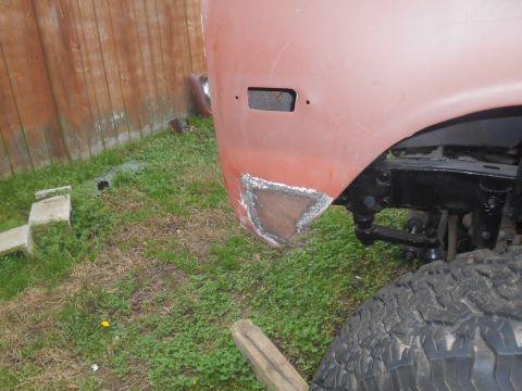 1972 Ford Bronco - A close-up view of the lower front fender area of a vehicle undergoing repair, showing a patch of metal welded into place. The vehicle is r…