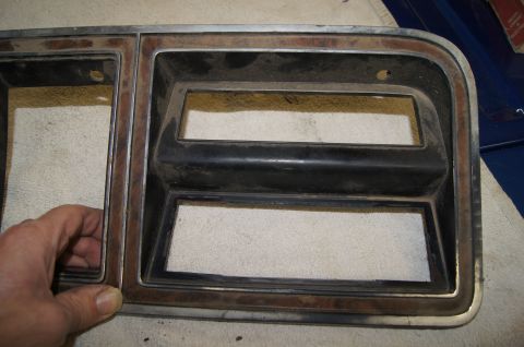 1979 Ford Bronco - A person's hand is holding a weathered, rectangular vehicle trim piece with two large rectangular cutouts. The trim has a chrome outer edge…