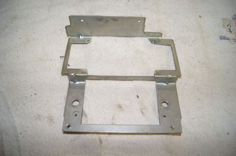 1979 Ford Bronco - A silver metal bracket with multiple holes and bends is shown lying flat on a textured white surface.