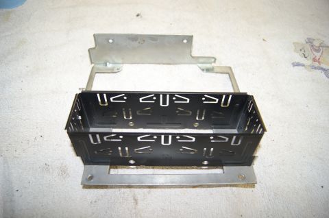 1979 Ford Bronco - A black metal car stereo mounting bracket is shown with a silver metal mounting frame above it. The bracket has multiple cutouts and slots…