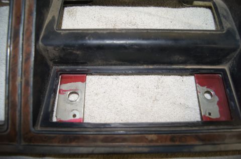1979 Ford Bronco - This is a close-up shot of a car's dashboard trim piece. The trim has a faux wood grain finish on the left and black plastic surrounding tw…