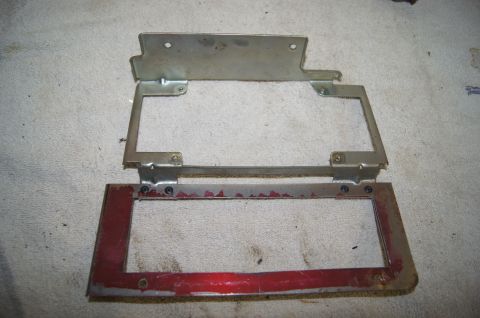1979 Ford Bronco - Two metal brackets, one with red paint, are laid out on a textured surface. The brackets appear to be part of a vehicle's interior or engin…