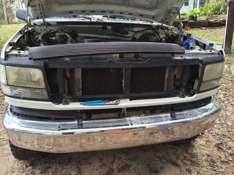 1996 Ford Bronco front end with hood open, installing new chrome grille.