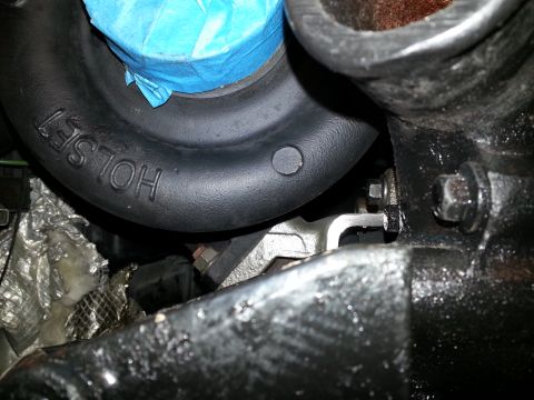1994 Ford Bronco - A close-up view of a black turbocharger housing with the embossed text "HOLSET" visible. The turbo is connected to a dark, greasy engine co…