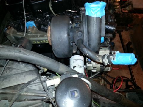 1994 Ford Bronco - A close-up view of a turbocharger and related engine components, likely from a 1994 Ford Bronco. Several parts are covered with blue tape.