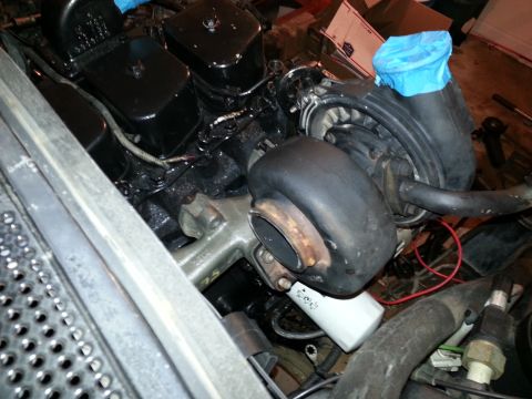 1994 Ford Bronco - Close-up view of a turbocharger and oil filter installed on a vehicle engine. The turbocharger is black with a rusty exhaust housing, and a…