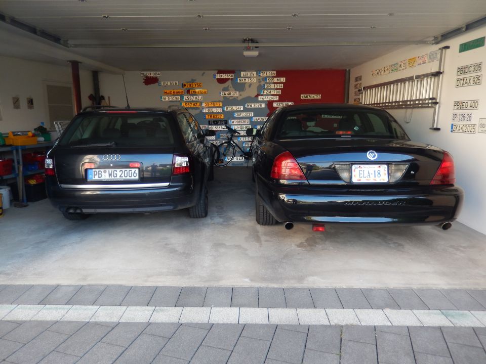 Two black cars parked in a garage, a Mercury Marauder and an Audi wagon.