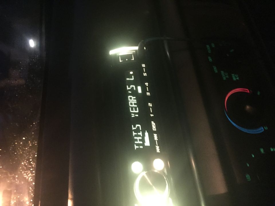 Car dashboard at night, showing a digital stereo display and climate controls.