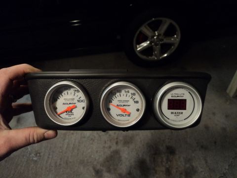 2004 Mercury Grand Marquis - Three Auto Meter gauges are shown in a housing, with a car wheel visible in the background.