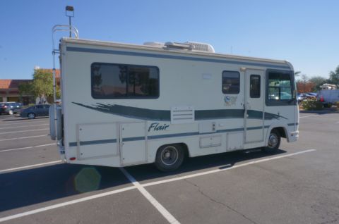 1995 Chevrolet P30 1 Ton - Step Van - This RV is parked in a lot on a sunny day. The side of the vehicle shows a graphic design and the word 'Flair'.