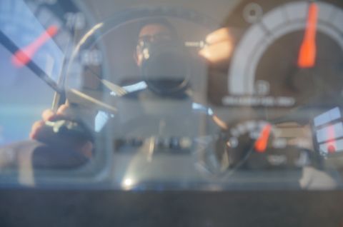 1995 Chevrolet P30 1 Ton - Step Van - Close-up of an automotive instrument cluster gauges seen through glass, with a person's reflection visible
