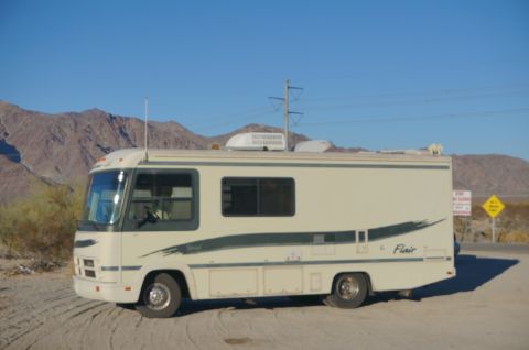 1995 Chevrolet P30 1 Ton - Step Van - A beige and green 1995 Chevrolet P30 step van, nicknamed "Flair 22D", is parked on a dirt road with mountains in the background under a cle…
