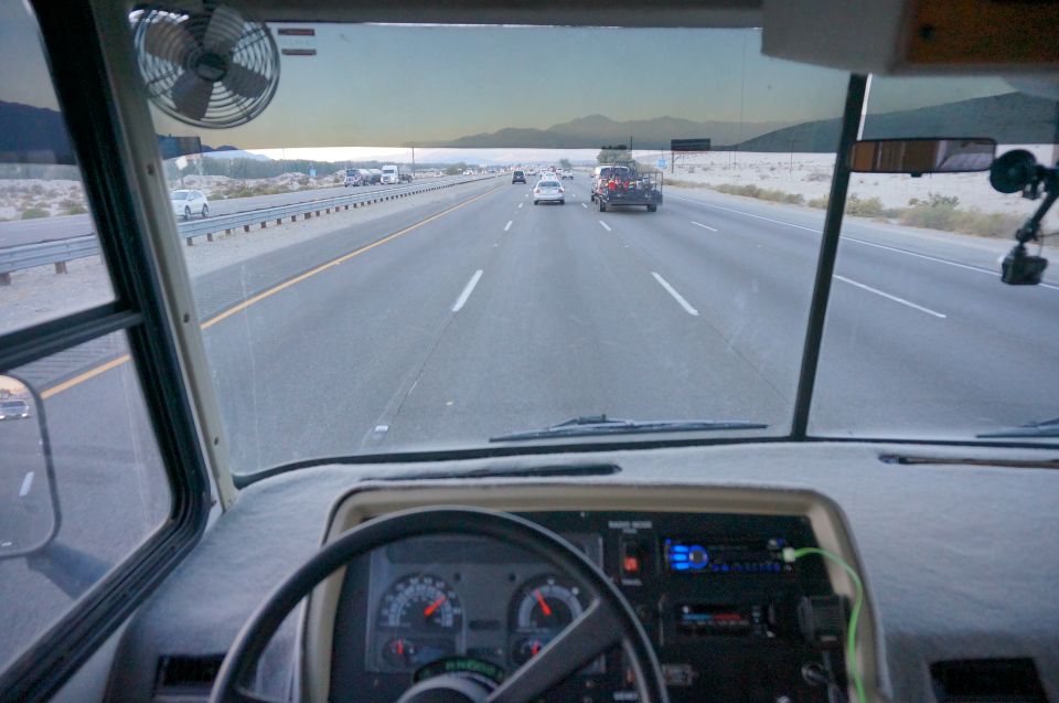 View from inside a step van driving on a highway in the desert.