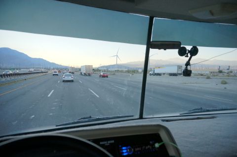 1995 Chevrolet P30 1 Ton - Step Van - View from the driver's seat of a motorhome driving on a highway towards mountains, with wind turbines visible in the distance.