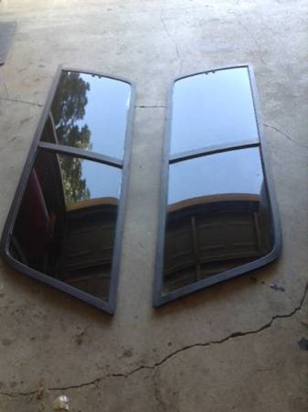 1981 Ford Bronco - Two dark tinted side windows with black frames are laid out on a concrete surface. The windows appear to be for a vehicle, possibly a Ford…