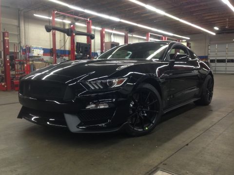 1992 Ford F-150 - A black sports coupe is parked inside a garage with lifts in the background.
