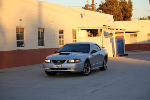 2002 Ford Mustang - A silver 2002 Ford Mustang is parked in an outdoor lot with a building in the background.