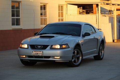 2002 Ford Mustang - A silver 2002 Ford Mustang coupe is shown from a three-quarter front angle in front of a building.