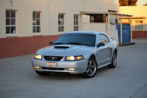 2002 Ford Mustang - A silver 2002 Ford Mustang coupe is parked outside a building during the day.
