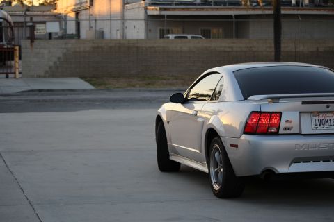 2002 Ford Mustang - The rear driver's side quarter of a silver Ford Mustang GT is shown parked on a concrete surface. The car has a California license plate re…