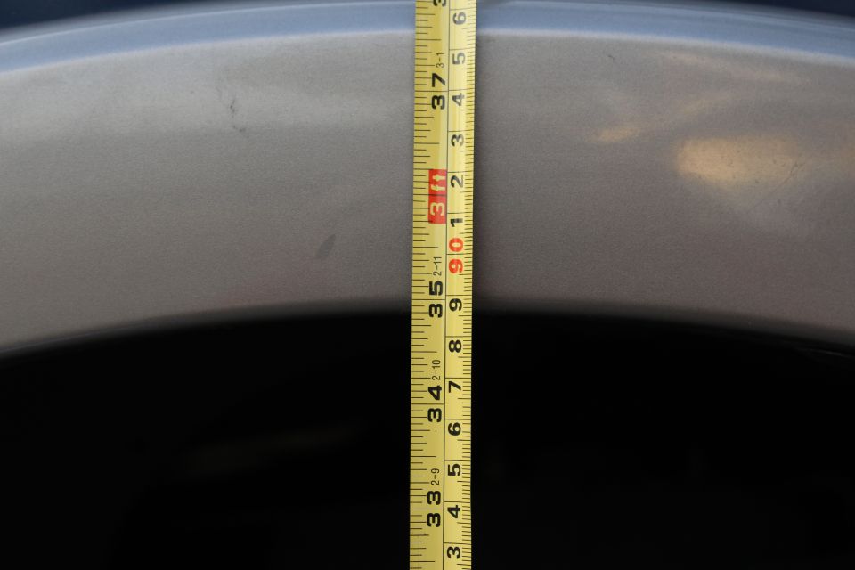 Close-up of a measuring tape on a silver vehicle body panel.