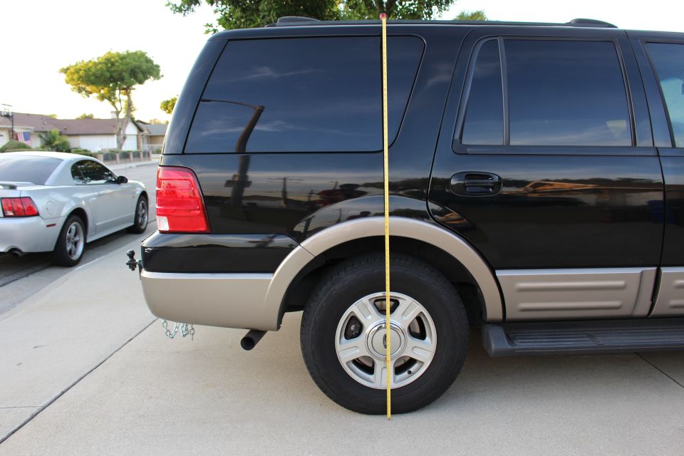 Black and tan Ford Expedition SUV with a measuring tape next to it.