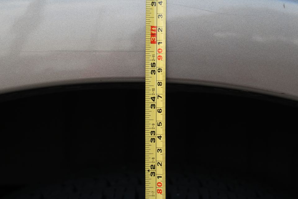 Measuring tape against silver SUV wheel well, showing 32-35 inches.