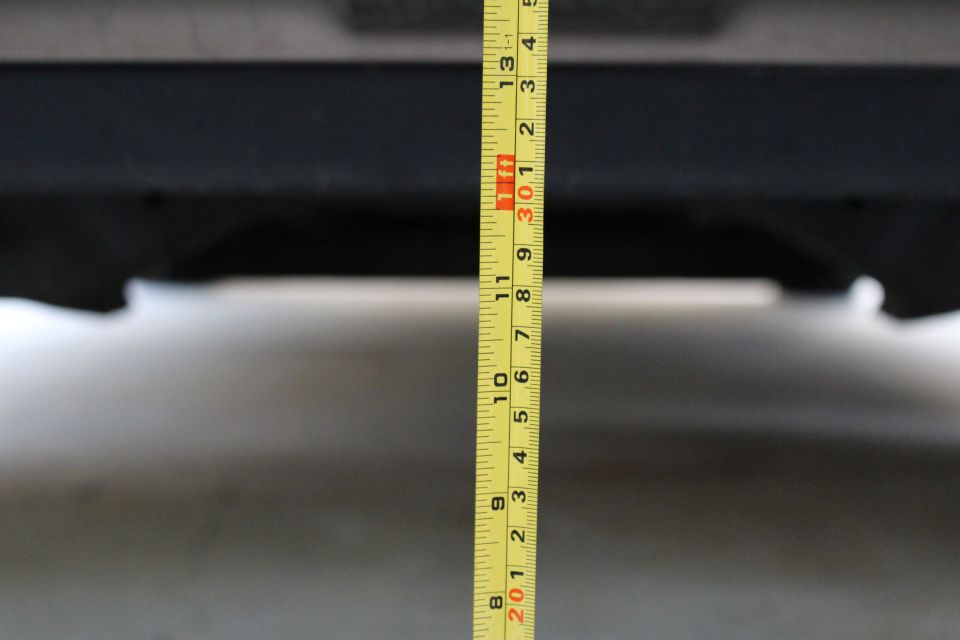 Yellow measuring tape showing inches and feet against a dark surface.