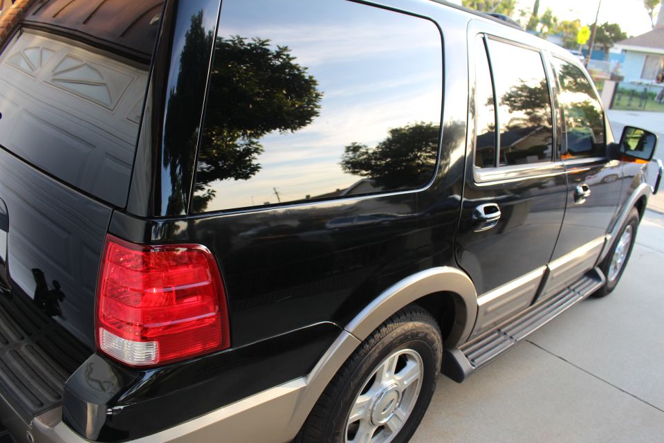 Black Ford Expedition, rear driver's side view, parked on driveway.