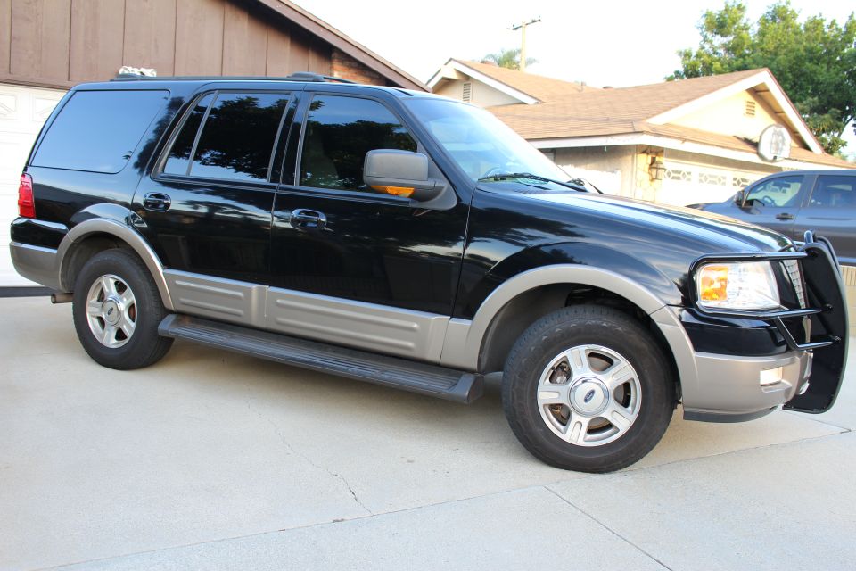 Black Ford Expedition SUV parked on a driveway, showing passenger side with brush guard.