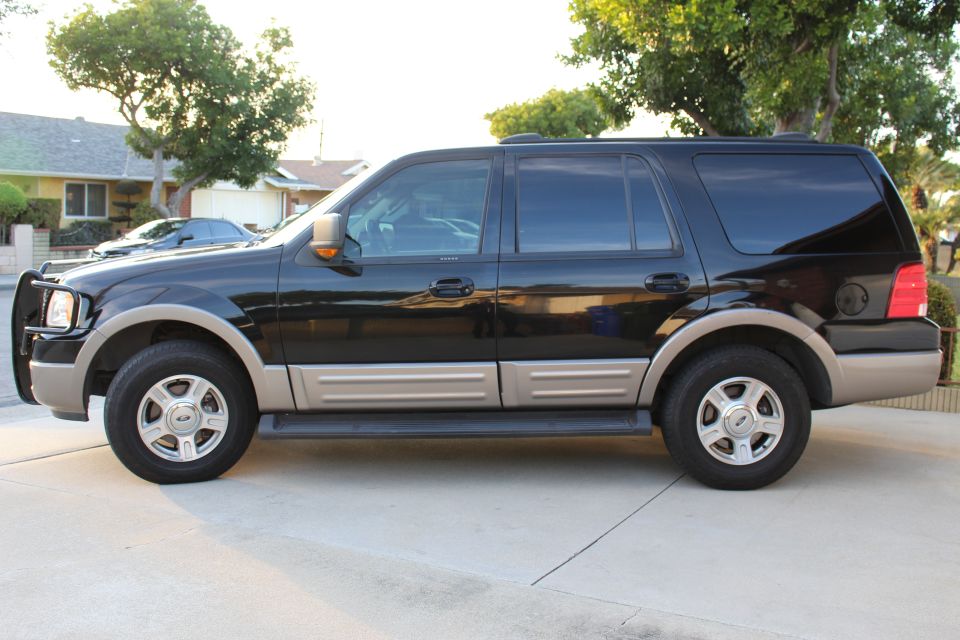 Side view of a black Ford Expedition SUV with tan trim and a brush guard.