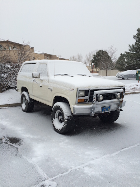 1981 Ford Bronco - A white Ford Bronco is parked in a snow-covered lot. The vehicle has a light dusting of snow on its exterior, and the tires are also covere…